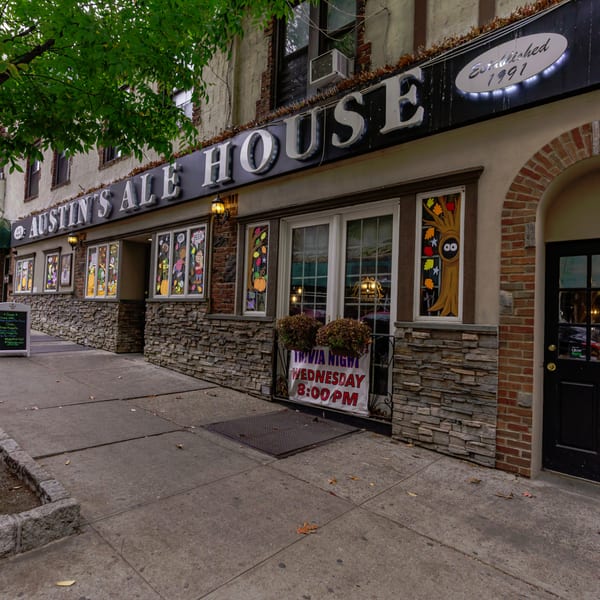 Exterior of Austin's Ale House with stone facade, decorative windows, and a "Trivia Night" sign.