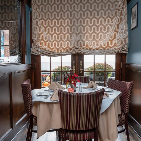 A set dining table with four chairs, a floral centerpiece, and a window view at Austin's Ale House.
