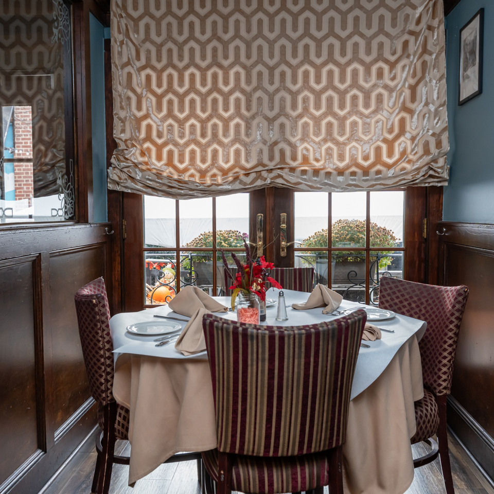 A set dining table with four chairs, a floral centerpiece, and a window view at Austin's Ale House.