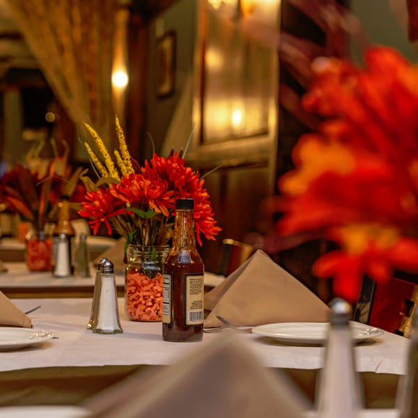 A restaurant table set with plates, napkins, salt and pepper shakers, and a hot sauce bottle.