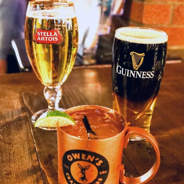 Stella Artois, Guinness, and an Owen's Craft Mixers drink on a wooden table at Austin's Ale House.