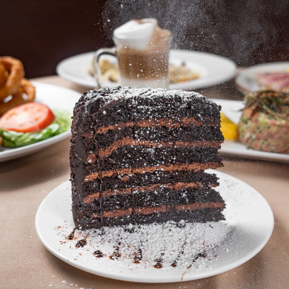 A slice of Austin's Ale House chocolate cake with powdered sugar falling onto it.