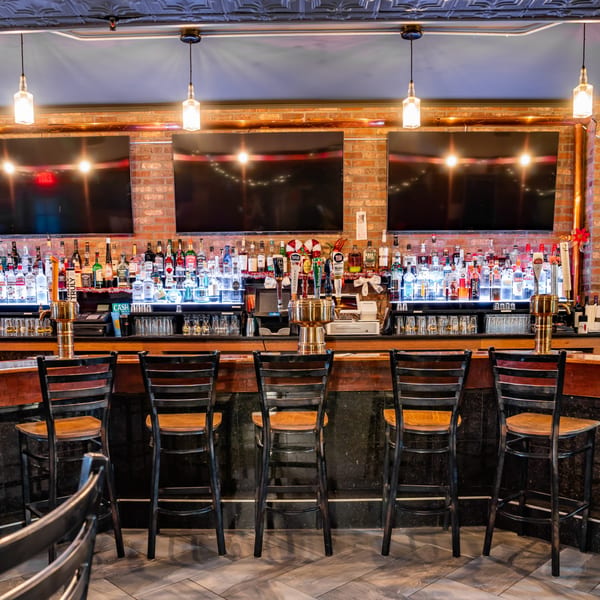 Austin's Ale House bar with liquor bottles, beer taps, and empty bar stools.
