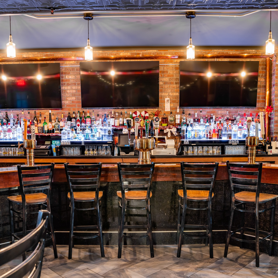 Austin's Ale House bar with liquor bottles, beer taps, and empty bar stools.