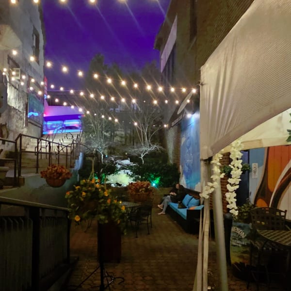 Austin's Ale House outdoor patio at night, with string lights, seating, and a person relaxing.