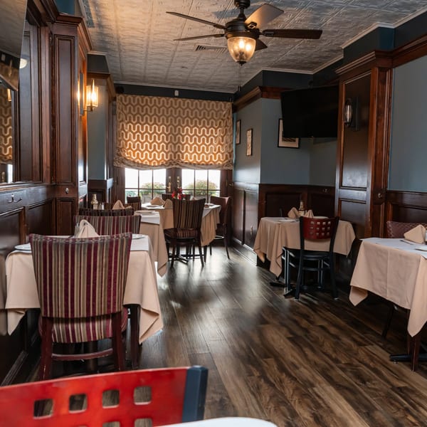 The Austin's Ale House dining room features dark wood paneling, blue walls, and set tables with striped chairs.
