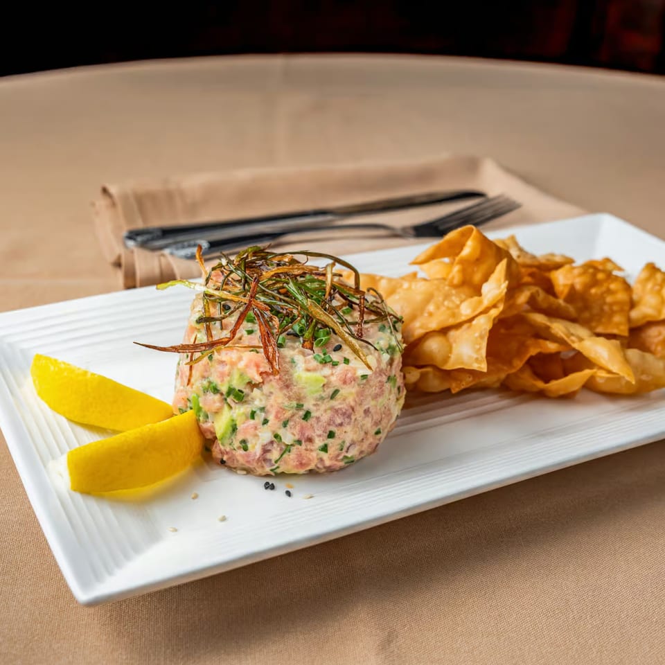 Austin's Ale House salmon tartare with avocado, chives, crispy onions, lemon wedges, and wonton chips.